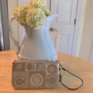 Tan and beige Coach wristlet in patchwork pattern.